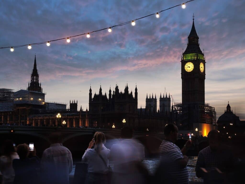 Big Ben in London at night with tourists taking pictures